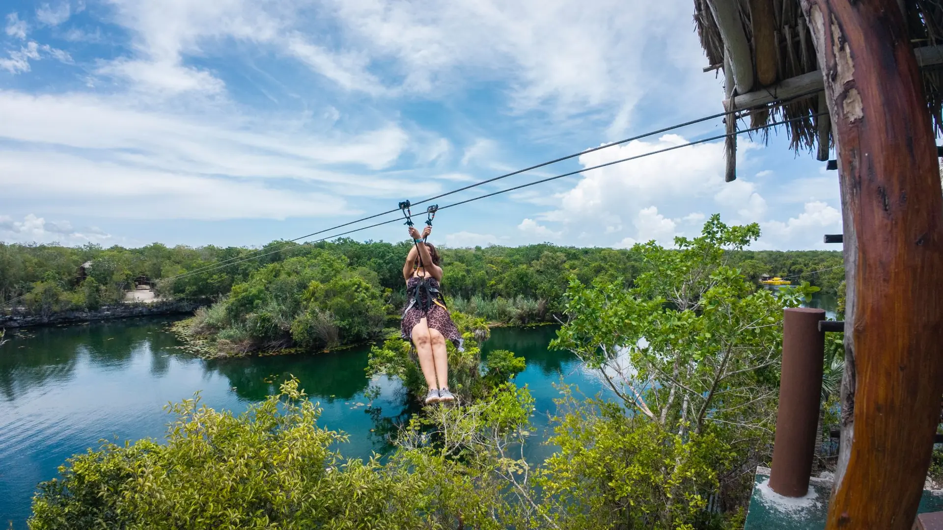 Guest ziplining over a turquoise lagoon in the jungle