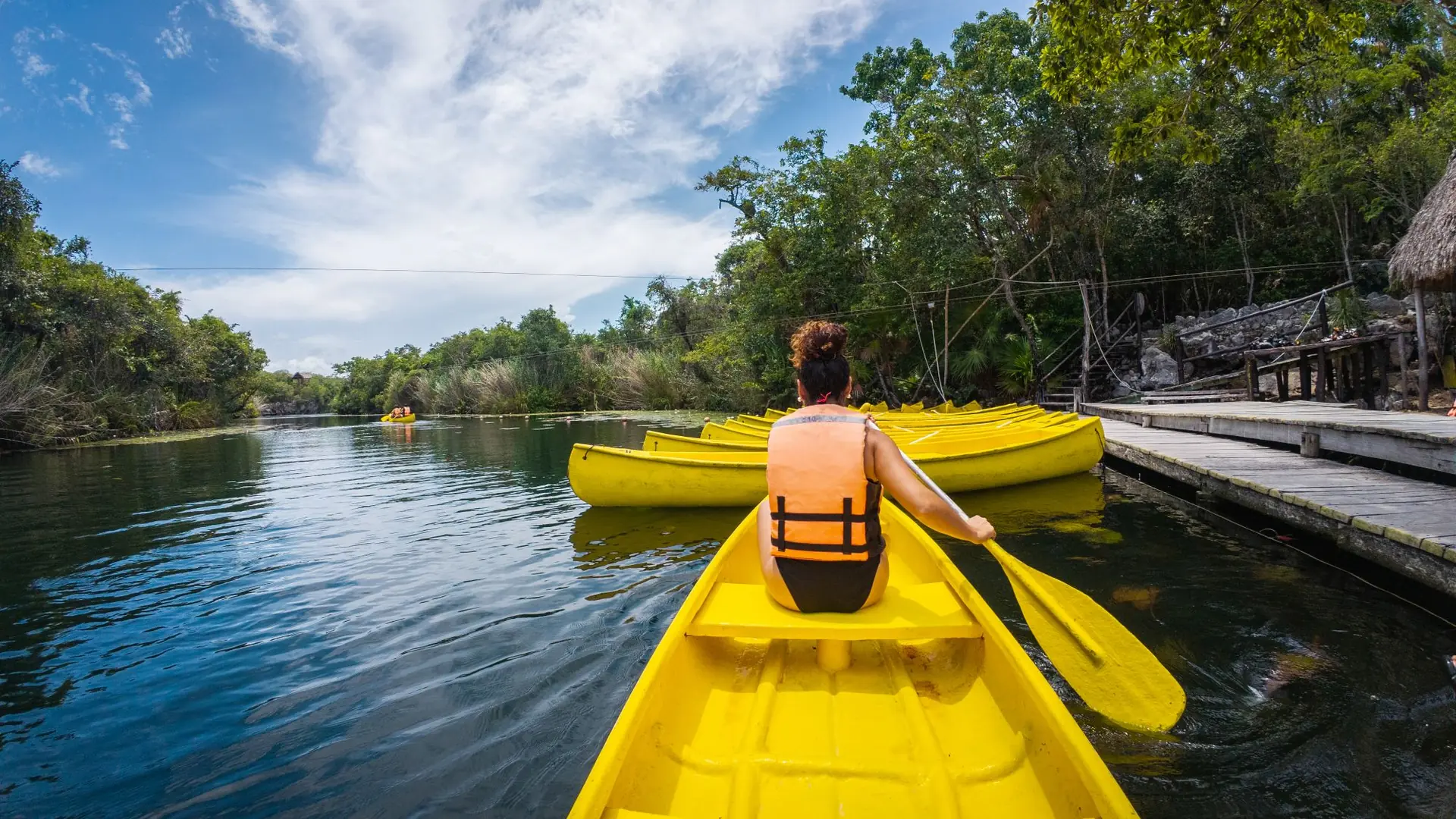 Guest paddling a yellow canoe on a calm jungle lagoon