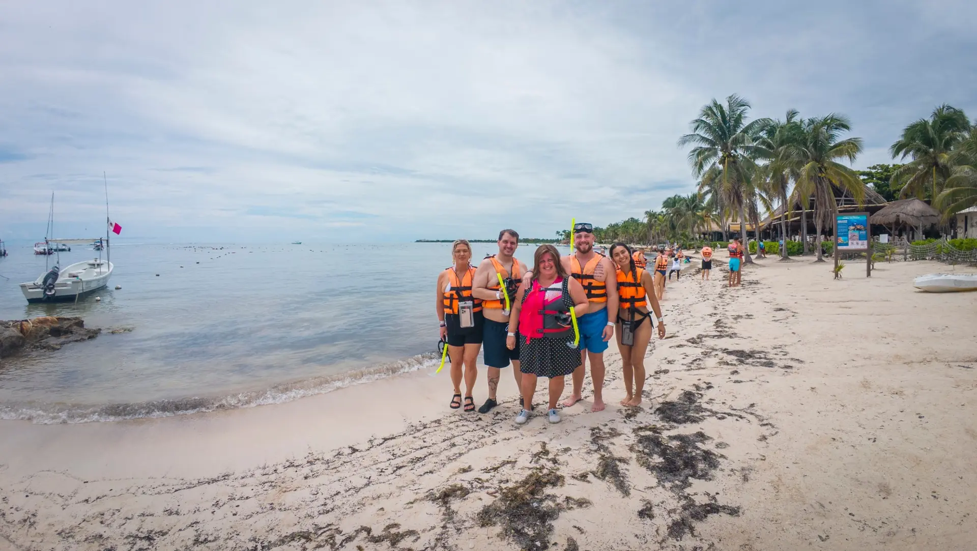 Group of guests in life jackets with snorkels on a white sand beach